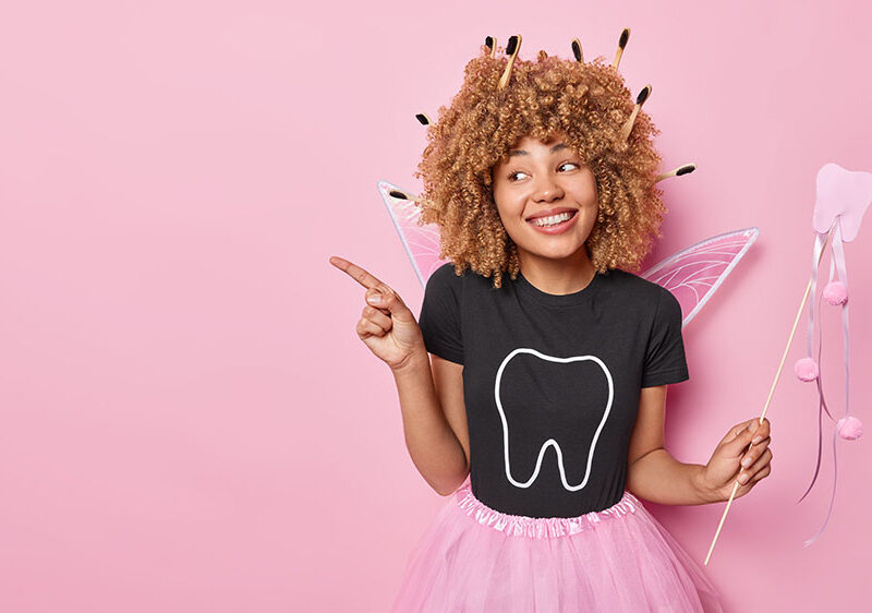 Women smiling dressed as the tooth fairy on a pink background